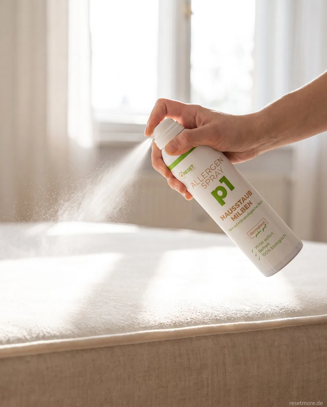Eine Hand sprüht Allergen Spray p1 aus rund 25 cm Abstand auf eine helle Matratze